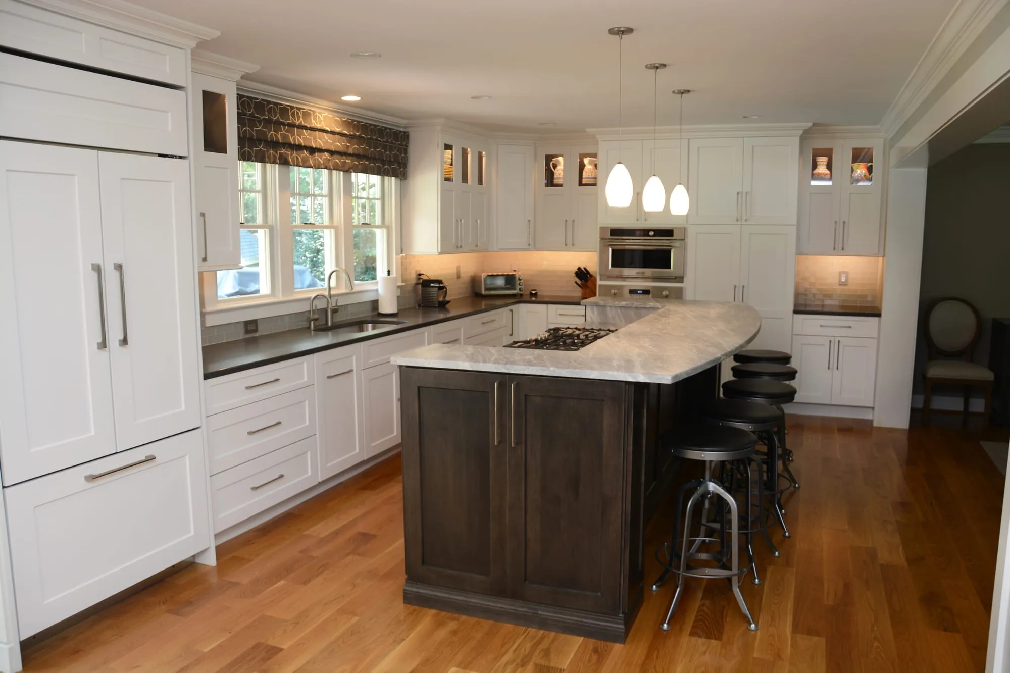 Kitchen by Pondside Kitchens with white Brighton perimeter cabinetry, a walnut island and stone countertops