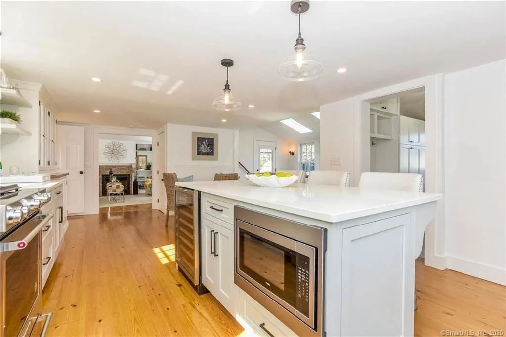 Wide view of a white Brighton inset kitchen in Essex CT with wide-plank wood floors