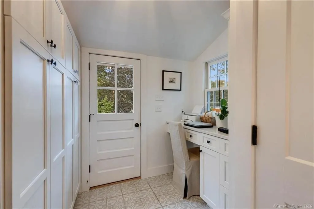 Mudroom with white built-in cabinets, bench and hooks in Essex CT