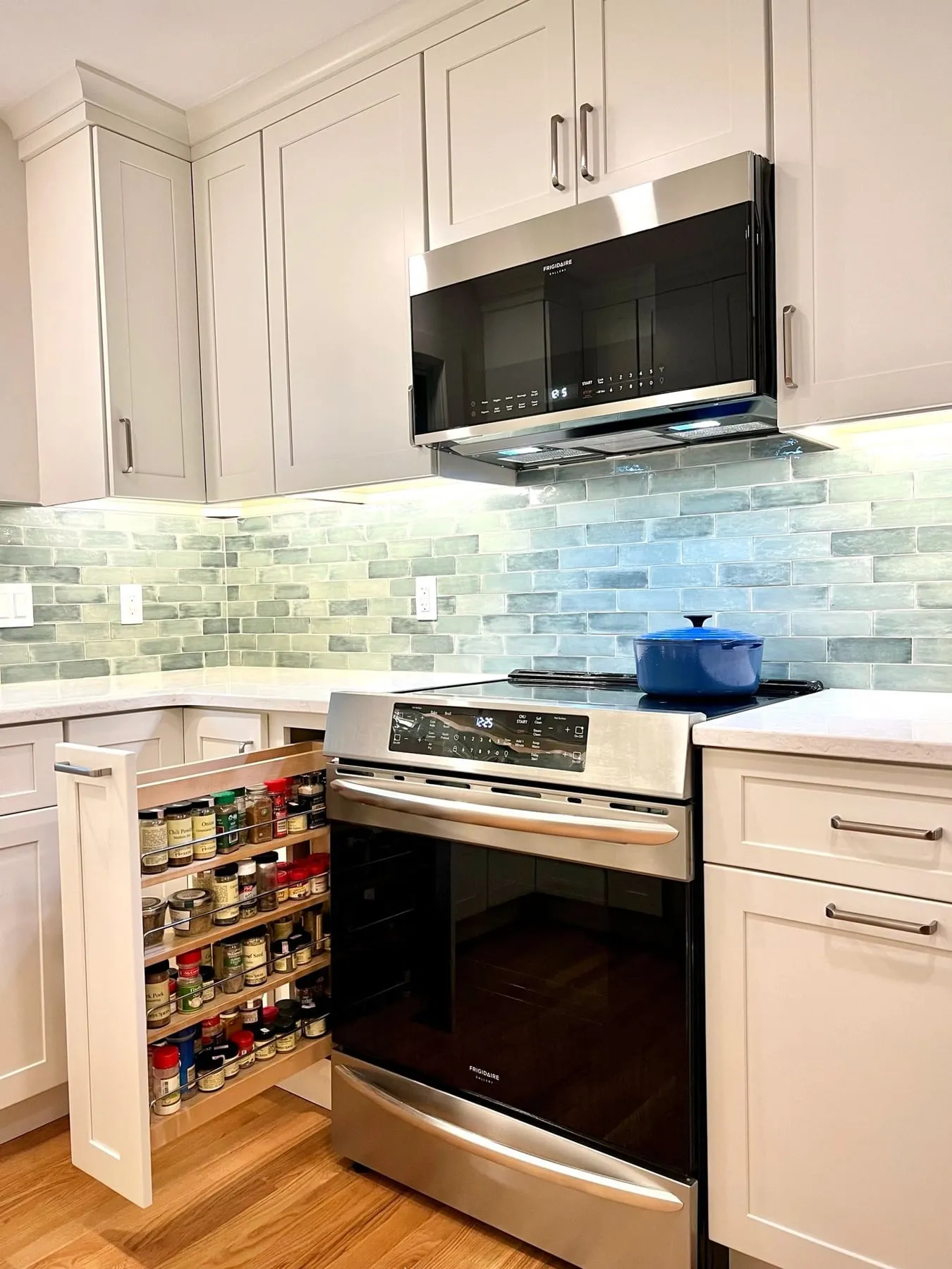 Range wall with white cabinets, sage tile and stainless microwave hood in Guilford CT