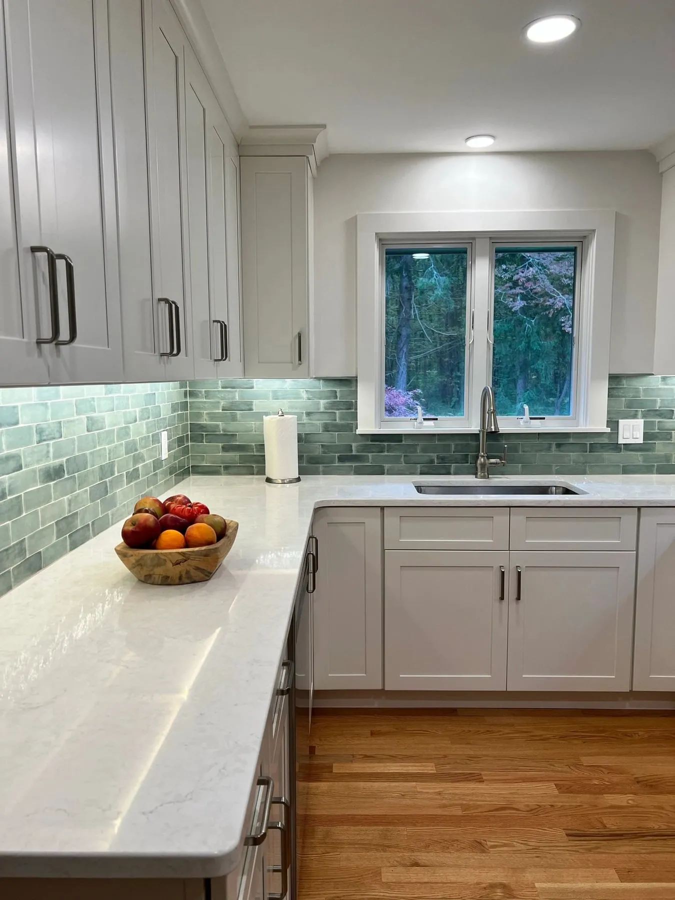 Corner of a white kitchen with sage green tile and quartz counters in Guilford CT
