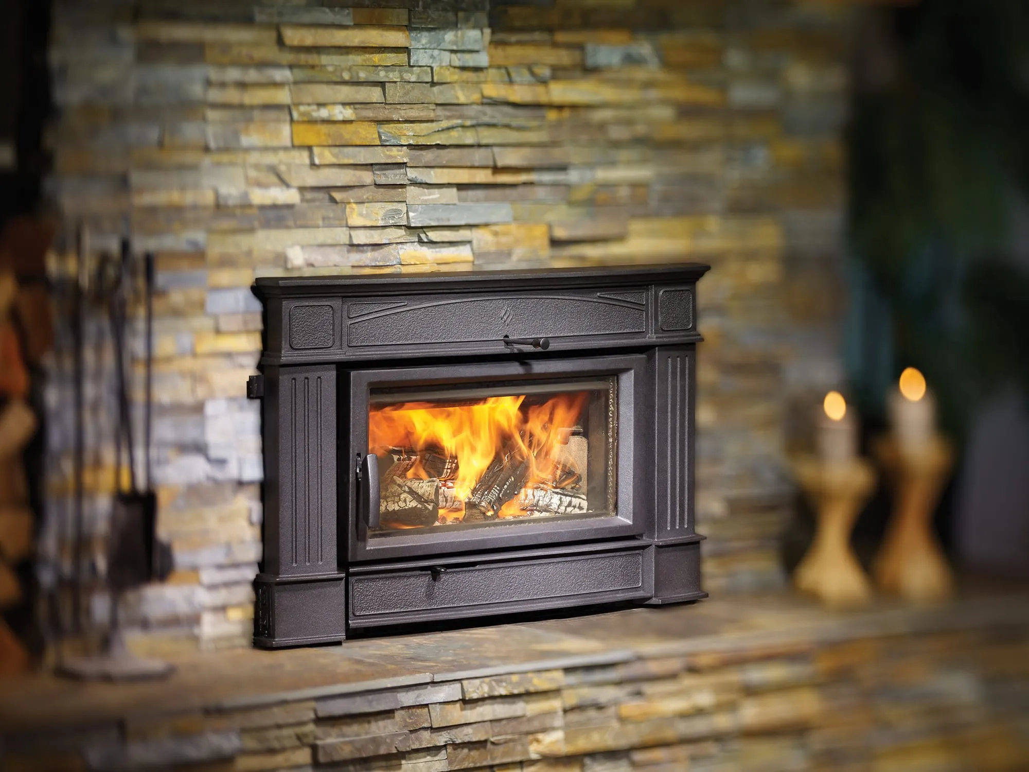 Regency HI500 wood fireplace insert burning in a stacked stone fireplace