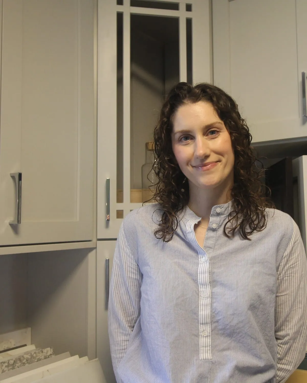 Stacey Dady of Pondside Kitchens, in front of cabinet door samples in the Deep River showroom